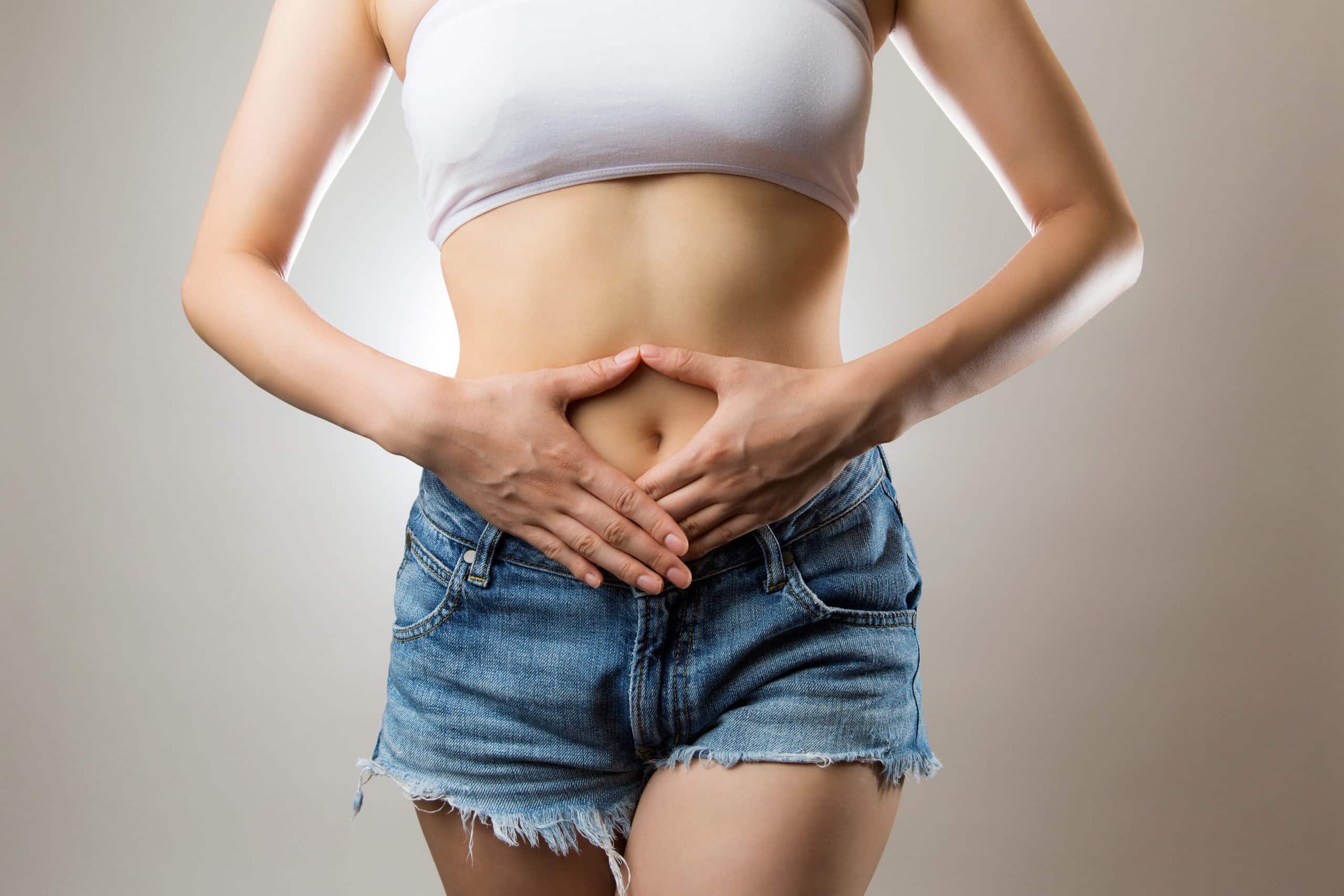 woman with hands on stomach hoping to heal her gut and restore gut health